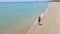 Slowmotion Aerial shot of a young woman running on a beautiful beach. Concept of healthy lifestyle and sports