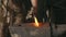 Slowmotion closeup blacksmith hands manually forging hot metal on the anvil in smithy with spark fireworks