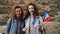 Slowmotion portrait of two laughing women students waving French flags and looking at camera standing against brickwall