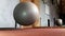 A slowmotion shot of a big pilates ball getting kicked by a foot at a gym