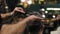Slowmotion shot: Closeup view of the barber`s hands performing a haircut with scissors and combing the client