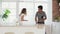 Slowmotion shot of happy young couple dancing listening to music in the kitchen wearing pajamas. Multiethnical couple in
