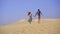 Slowmotion shot of a young woman and man running together in a desert