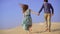 Slowmotion shot of a young woman and man running together in a desert