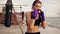 Slowmotion shot: young woman shadow boxing with her hands wrapped in purple boxing tapes looking in the camera