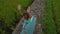 Slowmotion steadicam shot of a young woman with yoga math walking through a beautiful rice field