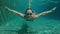 Slowmotion underwater shot of a happy woman dive in a swimming pool. Healthy lifestyle concept