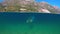 Slowmotion. Woman snorkeling at the sea. Half view of ocean and mountains.