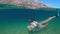 Slowmotion. Woman snorkeling at the sea. Half view of ocean and mountains.