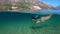 Slowmotion. Woman snorkeling at the sea. Half view of ocean and mountains.