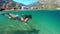 Slowmotion. Woman snorkeling at the sea. Half view of ocean and mountains.