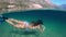 Slowmotion. Woman snorkeling at the sea. Half view of ocean and mountains.