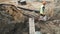 Slowmotion worker in orange hard hat walk circular saw in ditch at building site