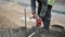 Slowmotion worker in red gloves hammering iron rod in ground with sledgehammer