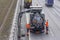 Sludge washer truck suction machine and workers specialists at work on the side of the highway to clean underground infrastructure