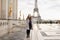 Smaling woman standing on Trocadero square near gilded statues and Eiffel Tower.