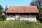 Small abandoned old wooden family house with dilapidated boards and missing roof tiles on top of small hill surrounded with grass