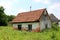 Small abandoned ruined brick house surrounded with tall uncut grass