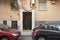 Small access portal door to an old basement apartment building with barred windows and some plants