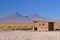 Small adobe house in the desert on salt terrain and near two vol