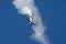 Small aircraft is executing an air stunt, leaving behind a vibrant vapor trail in the sky
