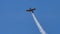 Small aircraft flying at high speed over an airfield in sunny day with blue sky