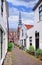 Small alleyway with white plastered houses and a church on the background, Gouda, Netherlands.