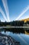 A small alpine lake in the Swiss Alps in early autumn and just before sunset. The water is calm and reflects the fir forest on the