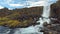 Small amazing waterfall Oxararfoss and river in Iceland, basalt rocks and yellowed grass in autumn