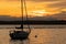a small anchored sail boat floating at golden hour