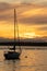 a small anchored sail boat floating at golden hour