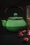 A small Asian type green cast iron teapot along with dry tea and rosebuds