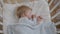 Small attractive baby sleeps soundly during day on a soft comfortable pillow covered with a blanket in crib