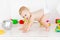 A small baby boy six months old crawls through in a light white nursery in diapers among toys