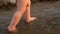 Small baby in diaper takes its first steps walking along river bank. Legs. Close-up. Slow motion