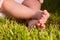 Small baby feet on the green grass at summer sunshiny day in the park.