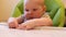 A small baby gets acquainted with food, the first bait of the child in children`s chairs in the kitchen