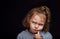 Small baby girl with serious angry face looking up and decided the question on black studio background. Closeup