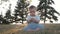 Small baby girl sitting on grass in park. Beautiful baby portrait in nature