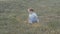 Small baby girl sitting on grass in park. Beautiful baby portrait in nature