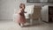 Small baby toddler girl in tutu skirt and dress near the sofa learns to walk