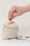 In a small bag, standing on a white background, the hand folds coins. Vertical photo, close-up. Russian money. The idea is