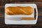 Small baguette, knife on cutting board on wooden table. Top view