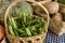 A small basket filled with Baguio Beans, alongside squash, potatoes and other vegetables at a weekend market