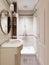 A small bathroom with a shower and toilet and ceramic tiles on the walls and floor is beige