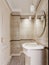A small bathroom with a shower and toilet and ceramic tiles on the walls and floor is beige