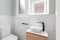 Small bathroom with toilet and designer sink on small vanity with black faucet. Walls of room are made of white natural