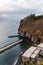 Small beach full of colorful sunbeds and umbrellas next to high cliff