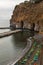 Small beach full of colorful sunbeds and umbrellas next to high cliff