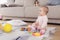 A small beautiful baby sits on the floor and plays with bright, flowery toys.